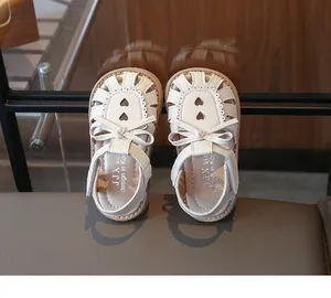 Detail von weißen Mädchen-Sandalen mit Schleife und herzförmigem Lochmuster