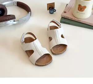 Top view of cream kids sandals with velcro straps and cork sole in a cozy setting