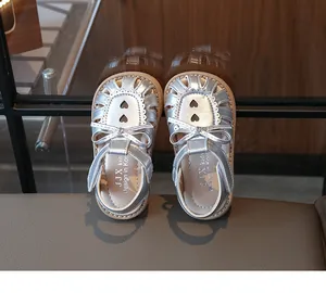 Nahaufnahme der silbernen Kindersandalen mit Herz-Ausschnitten und Schleife