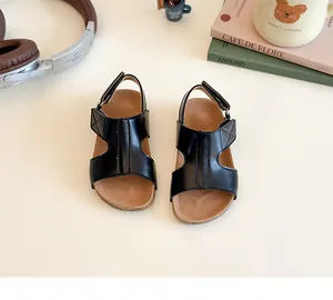 Close-up of black kids cork sandals with double adjustable straps on a lifestyle background