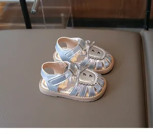 Nahaufnahme silberner Babysandalen mit Schleifenverzierung und Herz-Hohlmuster-Design