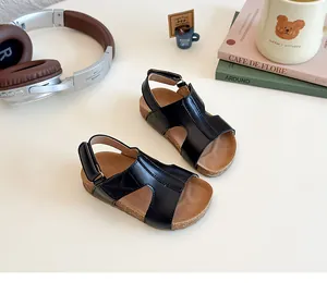 Detail of black leather kids' sandals with velcro straps and cork-style thick soles