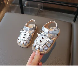 Details von silbernen Kinder-Sandalen mit Schleife und Herz-Ausschnitten