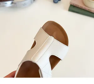 Close-up of white leather H-cut slides with brown cork-style footbed and fine stitching