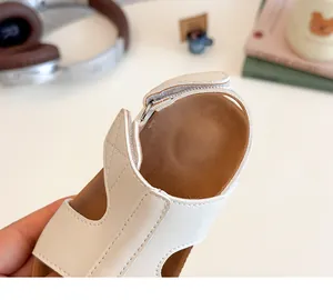 Detail of soft cream leather upper and non-slip brown textured footbed of kids sandals