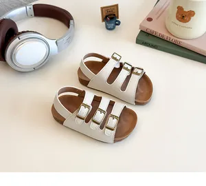 Détail de sandales pour enfants avec sangles en similicuir blanc cassé et boucles en bronze