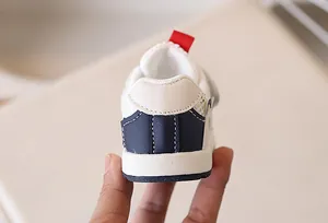 Detail of baby sneakers showing breathable mesh, navy leather panels and heel pull tab