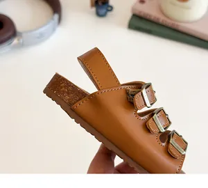 Détail de sandales enfant en cuir marron avec boucles réglables et semelle aspect liège