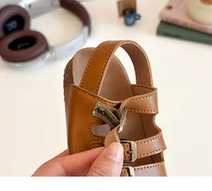 Détail de sandales enfant en cuir marron avec boucles en métal et semelle texture liège