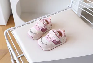 Dettaglio delle scarpe da camminata per neonati rosa con velcro su una sedia bianca
