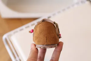 Detail van leren kinderschoenen met hielstiksels en roze kraalaccenten van opzij