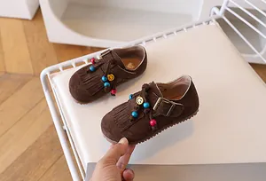 Macro-detail van bruine suède loafers voor kinderen met kwastjes en kleurrijke kralen
