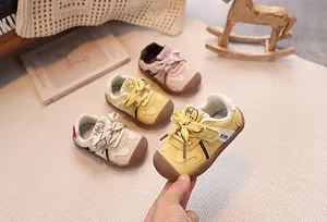 Detail of infant sneakers with bow accents, non-slip rubber toe caps and velcro straps