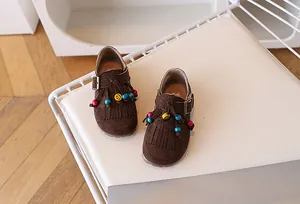 Detail van leren kinderschoenen met franjes, kleurrijke kralen en gele smiley-decoratie