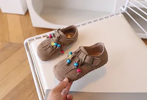 Detail van bruine suède kinderloafers met franjes en kleurrijke kralen als decoratie