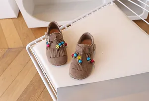Close-up van bruine suède kinderschoenen met franjes en kleurrijke kralen