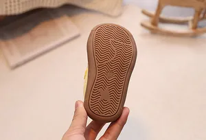Detail of baby sneakers showing the brown rubber non-slip wavy pattern outsole with size 17/135