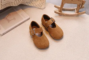 Gros plan détaillé de chaussures Mary Jane en daim marron pour filles sur tapis tissé