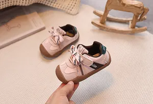 Close-up of pink baby sneakers featuring velcro strap and black white striped bow detail