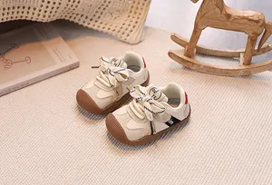 Detail of baby sneakers with striped bow tie and brown rubber toe cap on a cozy rug