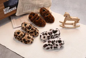 Three pairs of plush leopard print baby shoes on a cozy knit carpet background