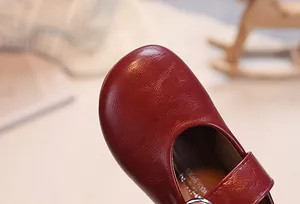 Close-up of girls' dark red Mary Jane shoes showing textured leather and round toe