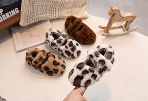 Detailed view of plush leopard print baby shoes with elastic straps on a soft rug