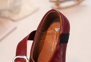 Detailed close-up of girls' red leather shoes showing stitching and heart inner lining