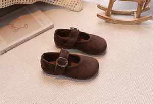 Gros plan sur des babies marron en daim pour filles avec boucle sur tapis tressé
