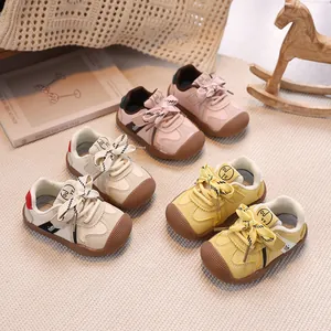 Pink and beige toddler sneakers with rubber toe caps on a soft nursery carpet