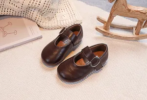 Close-up of retro brown Mary Jane shoes for girls with adjustable metal buckle on a cozy rug