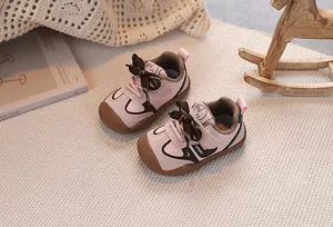 Pink and brown baby sports shoes with hook and loop closure on a cozy woven mat