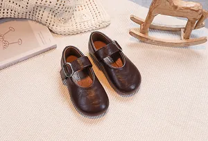 Detailed view of kids dark brown Mary Jane shoes with metal buckle on a cozy background