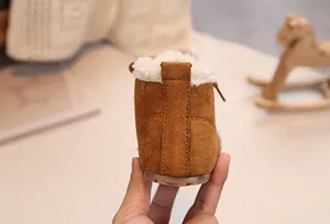 Close-up of winter baby boots with brown suede exterior and warm white faux fur lining