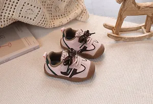 Detail of pink toddler sneakers with soft sole and reinforced toe on a beige carpet