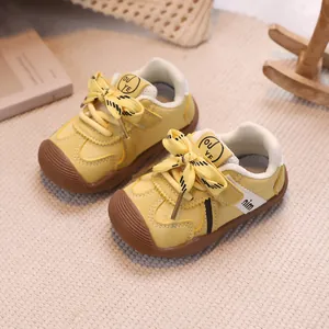 Yellow baby walking shoes with non-slip rubber toe and velcro closure on woven mat
