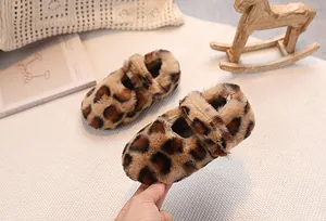 Detail of plush leopard print baby shoes on a cozy white rug with wooden decor