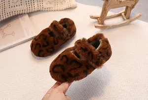 Close-up of leopard print faux fur baby shoes on a cozy white woven mat background
