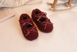 Detailed close-up of wine red faux fur Mary Jane shoes with patent leather bows on a cozy rug