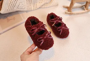 Detail of burgundy plush Mary Jane shoes featuring shiny double patent leather bows