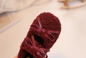 Detail of burgundy plush faux fur kids shoes featuring elegant leather bow accents
