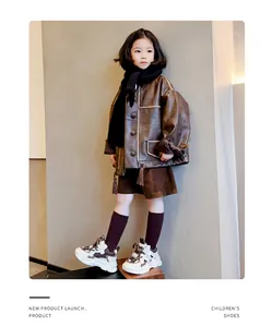 Detailansicht modischer Kinder-Chunky-Sneaker in Braun und Weiß mit einer Lederjacke kombiniert