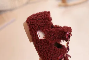 Detail of wine red plush Mary Jane shoes with velvet texture and leather bow detail