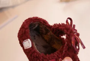 Detail view of burgundy plush baby shoes with thick warm lining and bow decoration