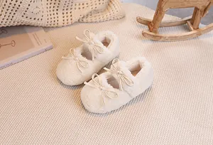 Detail of plush cream baby Mary Jane shoes with bow decoration in warm nursery setting