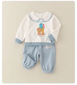 Detail of baby girl cotton set featuring blue polka dots and a cute cartoon bear print