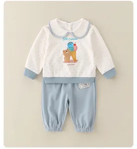 Flat lay of baby girl cotton set with polka dot top and blue lace waist pants