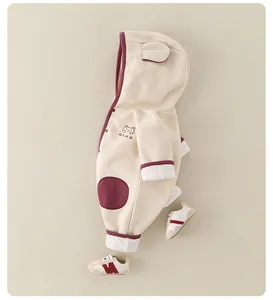 Détail de la barboteuse bébé avec broderie ours et capuche à oreilles en beige et marron
