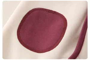 Détail macro d'une barboteuse en coton doux avec un patch bordeaux et des coutures soignées
