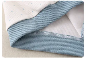Detail of baby cotton top featuring blue polka dots and soft ribbed cuff stitching